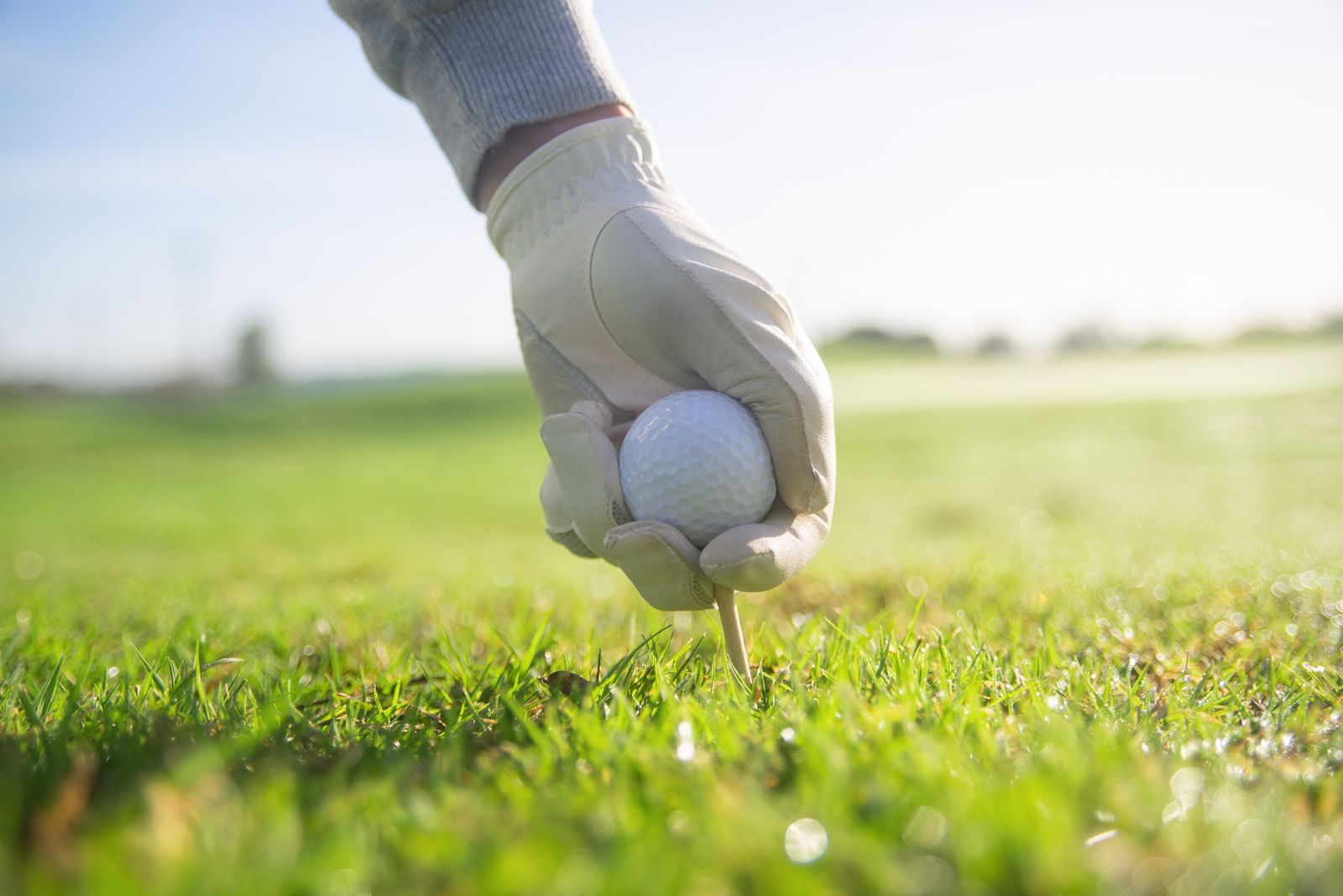 A hand placing a golf ball on a tee before testing